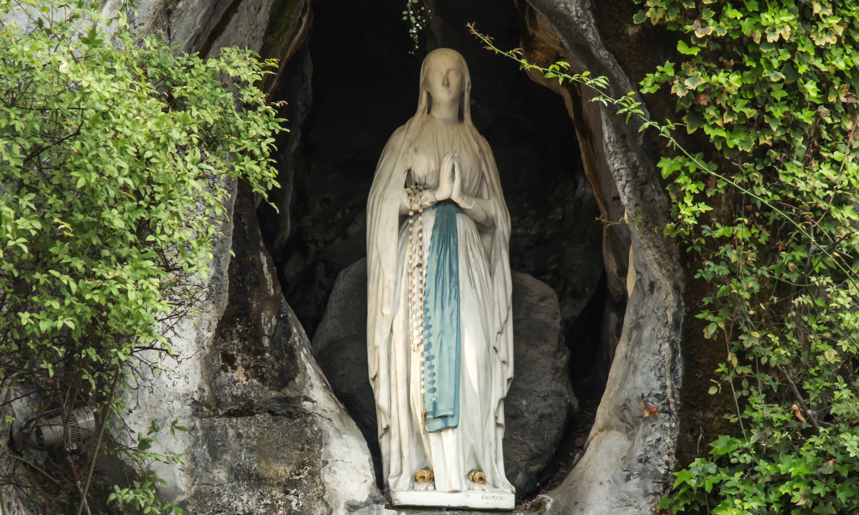 Statue of Our Lady of Immaculate Conception with a rosary in the Grotto ...